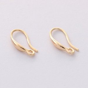 May include: Two gold-colored earring hooks. Each hook has a curved, teardrop-shaped body with a small loop at the bottom and a straight wire extending from the top. The hooks are designed for jewelry making.