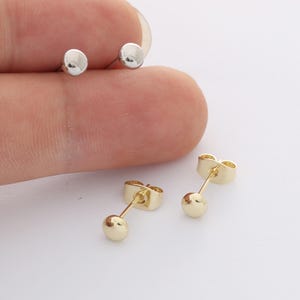 Peut inclure: Deux paires de petites boucles d'oreilles à tige en forme de bille, une paire dans un ton argenté poli et une paire dans un ton doré poli. Chaque boucle présente une tête lisse, ronde et bombée fixée à une tige fine avec un fermoir papillon.