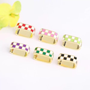 May include: Six gold-toned metal rings with a checkered pattern in various colors: red, pink, green, purple, and black. The rings have a rectangular shape with a gold base and a colorful checkered top.