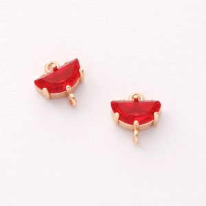 May include: Two gold-tone half-circle charms with red crystal accents and a loop for attaching to jewelry.