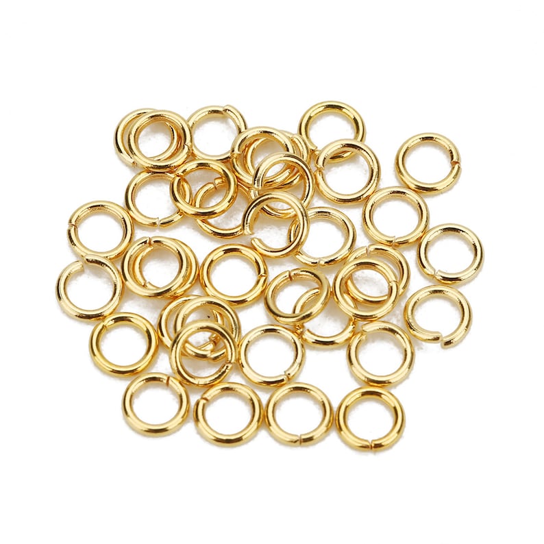 May include: A pile of gold jump rings, a type of jewelry finding used for connecting chains, cords, and other jewelry components.
