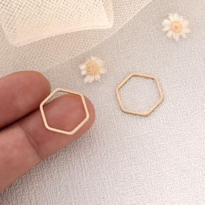 May include: Two gold-coloured hexagonal metal rings. The rings are approximately 2.5 cm in diameter and have a smooth, polished finish.