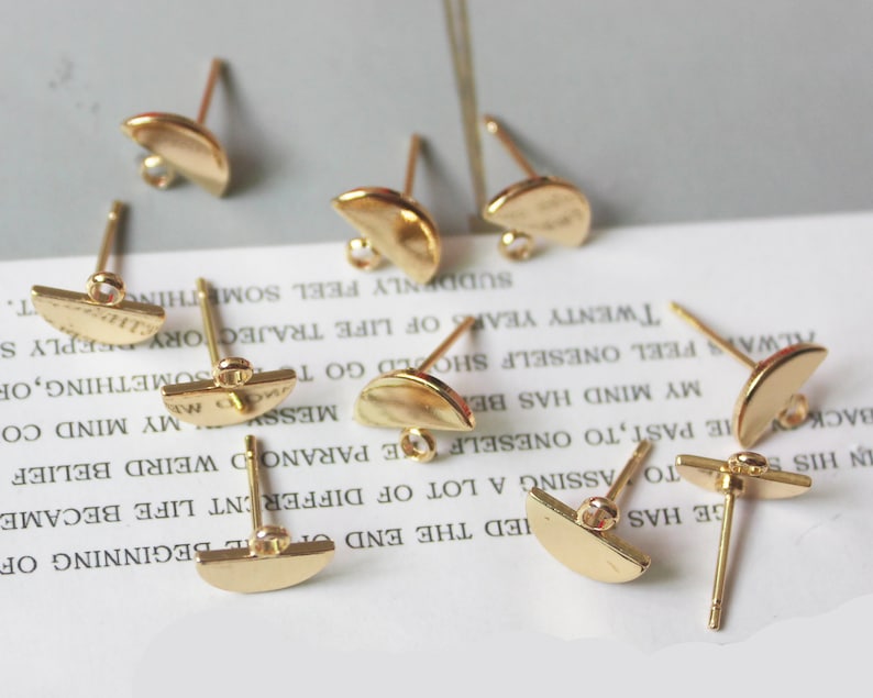 May include: Eight gold-toned earring posts with half-circle shaped tops. The posts are designed for use with jewelry making.