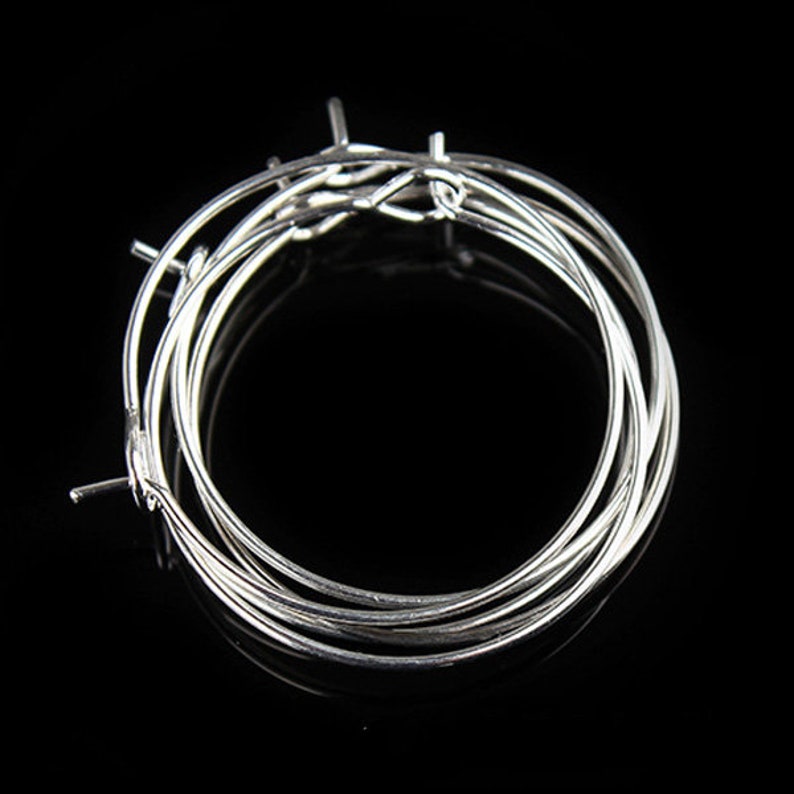 May include: A set of silver hoop earrings, stacked on top of each other. The hoops are thin and delicate, and they are perfect for everyday wear.