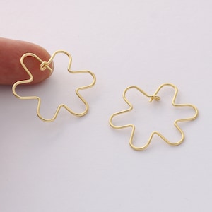 Pode incluir: Um par de brincos de argola de ouro em forma de flor. Os brincos são feitos de fio fino e têm um design simples e delicado.