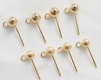 May include: Eight gold-toned earring posts with textured ball tops. The posts are straight and have a loop at the top for attaching to earrings.