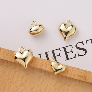 Puede incluir: Cuatro abalorios de metal de color dorado, dos en forma de coraz&oacute;n y dos en forma ovalada. Los abalorios tienen un bucle en la parte superior para sujetarlos a joyas u otras manualidades.