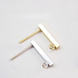 May include: Two earring posts with a rectangular bar and a jump ring at the end. One post is gold and the other is silver.