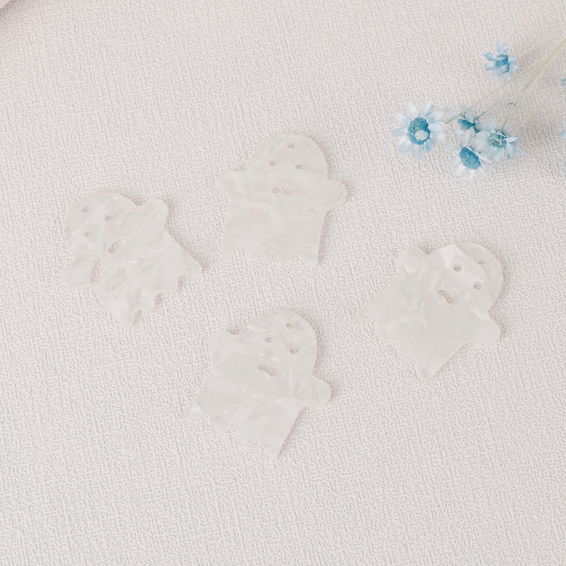 Puede incluir: Cuatro adornos blancos en forma de fantasma con una superficie texturizada.