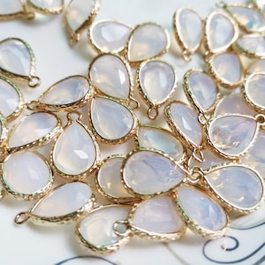 May include: A collection of teardrop-shaped, clear glass beads with gold-toned metal accents. The beads have a slightly iridescent finish and are strung on a gold-toned chain.
