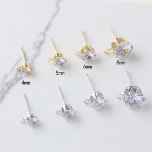 Pode incluir: Conjunto de postes de brincos de ouro e prata com pedras de zircônia cúbica transparentes. As pedras estão disponíveis nos tamanhos 4 mm, 5 mm, 6 mm, 8 mm.