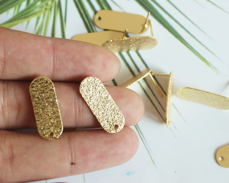 May include: Gold-toned metal oval earring blanks with a textured surface. The blanks have a small hole at the top for attaching earring findings.