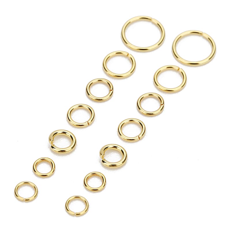 May include: A set of 12 gold jump rings in various sizes. The jump rings are arranged in two rows, with the largest rings at the top and the smallest rings at the bottom.