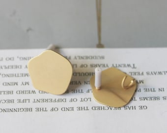 Puede incluir: Dos pendientes de color dorado con una forma única e irregular. Los pendientes tienen un cierre de poste y un pequeño gancho en el lateral.