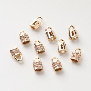 May include: Ten gold-tone padlock charms with clear rhinestones. The charms have a keyhole detail and are perfect for jewellery making or adding a touch of sparkle to your crafts.
