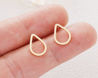 May include: A pair of gold-toned teardrop-shaped earrings with a hollow center.