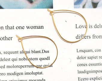Könnte beinhalten: Ein Paar goldene Tropfen-Ohrringe. Die Ohrringe sind aus dünnem Draht gefertigt und haben ein schlichtes, elegantes Design.