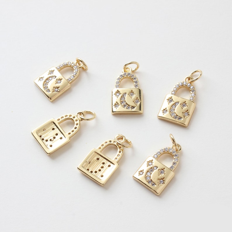 May include: Six gold-tone padlock charms with clear crystal embellishments. Some charms feature a crescent moon and stars design, while others have a geometric pattern.