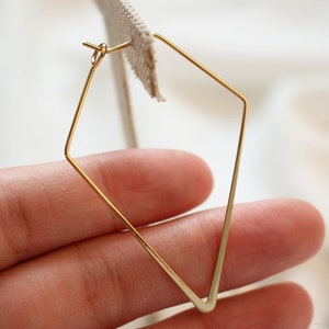 May include: Gold-toned geometric hoop earrings with a diamond shape.