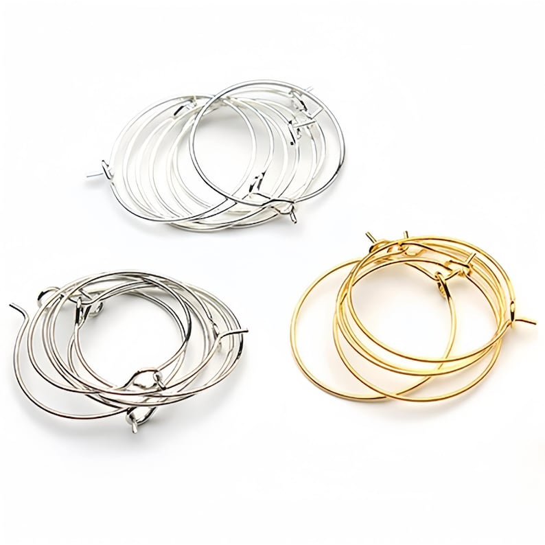 May include: A set of six hoop earrings, three silver and three gold, with a simple, circular design. The earrings are made of thin metal and have a hinged closure.