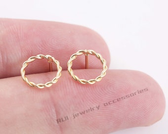 May include: A pair of gold-toned, twisted wire circle stud earrings. The earrings are small and delicate, and they would make a great addition to any jewelry collection.