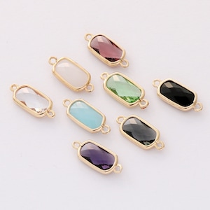May include: Eight gold-toned rectangular connector charms with faceted glass inserts in various colors: clear, white, light blue, green, black, purple, and two shades of gray.