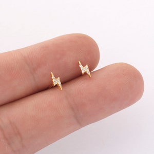 May include: A pair of gold lightning bolt stud earrings with clear cubic zirconia stones.