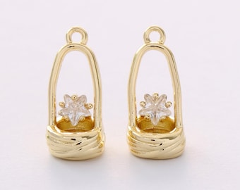 May include: Two gold-colored metal charms. Each charm features a star-shaped clear crystal set within a gold-colored basket-like structure. The top of each charm has a small loop for attachment. The charms are designed for jewelry making.