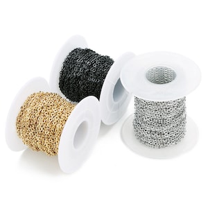 Pode incluir: Três rolos de corrente, um dourado, um prateado e um preto, são exibidos em um fundo branco. A corrente está enrolada em torno dos rolos.