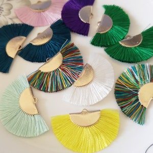 May include: Assortment of ten colorful half-circle fringe trim pieces with gold metal accents. The fringe is made of thin strands of fabric and is available in a variety of colors, including green, blue, pink, white, yellow, and multi-colored.