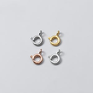 May include: Four silver, gold, and rose gold lobster clasps. The clasps are round and have a spring-loaded mechanism.
