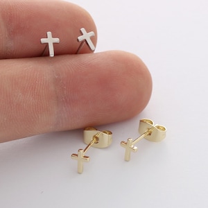 May include: A pair of silver-coloured cross stud earrings and a pair of gold-coloured cross stud earrings. Each earring features a small, simple cross design with a post back, showcasing a metallic finish and a clean, minimalist shape for everyday wear.