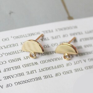 May include: Two gold-toned half-circle earring findings with a small clear bead on the loop of each finding.