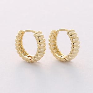 May include: A pair of gold hoop earrings with a textured, ribbed design.
