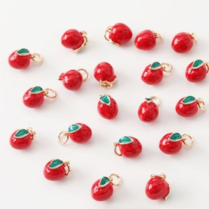 May include: A collection of 20 red apple charms with green leaves. Each charm has a gold loop for attaching to jewellery or other crafts.