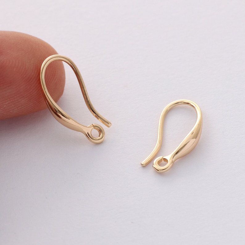 Pode incluir: Dois ganchos de brincos dourados. Os ganchos t&ecirc;m um design curvo com uma argola na parte inferior para prender os brincos. Os ganchos s&atilde;o feitos de um material met&aacute;lico brilhante.