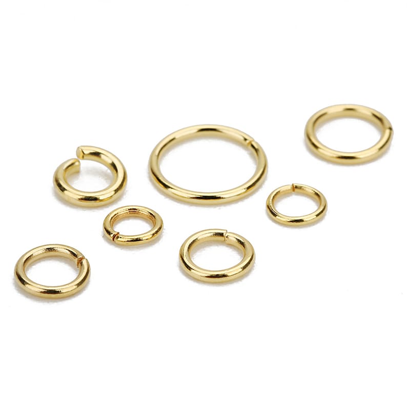 May include: A set of six gold jump rings of varying sizes. The jump rings are made of metal and have a smooth, polished finish.