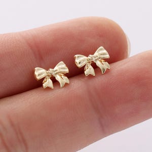 May include: A pair of gold bow-shaped stud earrings.