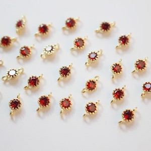 以下が含まれることがあります： 赤い宝石のアクセントが付いた、金色のジャンプリング20個のセット。各リングは、ジュエリーやその他のクラフトに取り付けるための小さなループが両側に付いています。