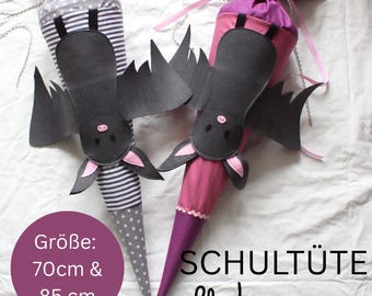 May include: Two cone-shaped fabric gift bags featuring black bat appliqués. One bag has grey and white stripes with grey star fabric, the other is solid magenta and purple. Text on the image indicates sizes of 70cm and 85cm and the word Schultüte.