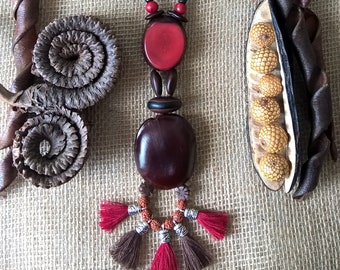 Ethnic necklace in vegetable ivory and tropical seeds decorated with cotton thread pompoms