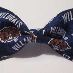 May include: A blue bow tie with a white and blue pattern featuring the Villanova Wildcats logo and the words "Wildcats" and "Villanova".