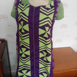 Peut inclure: Tablier sans manches violet avec un motif géométrique vert. Le tablier a une fermeture éclair sur le devant.