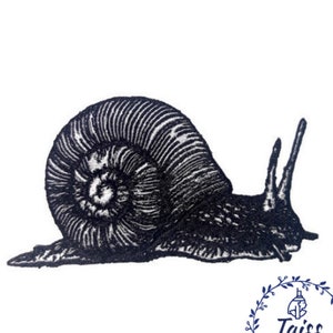 Op de afbeelding: Zwart-wit geborduurd ontwerp van een slak met een gedetailleerde schelp. De slak kruipt op een witte achtergrond.