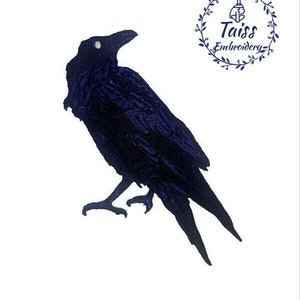 May include: A dark blue embroidered patch of a raven with a white eye, perched on a branch. The patch is for sewing or ironing onto fabric.