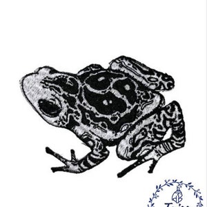 Może przedstawiać: Czarno-biała haftowana łatka przedstawiająca żabę z detalicznym wzorem. Żaba jest zwrócona w prawą stronę obrazu.