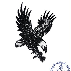 Puede incluir: Parche bordado en blanco y negro de un &aacute;guila en vuelo. El &aacute;guila est&aacute; mirando hacia la derecha y tiene las alas extendidas. Las garras del &aacute;guila est&aacute;n extendidas y parece que est&aacute; descendiendo en picado.