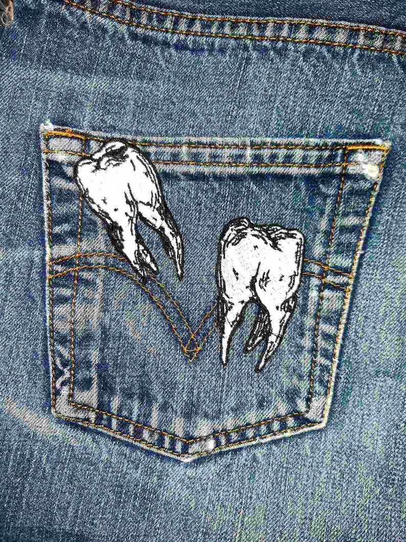 May include: A pair of white teeth embroidered on a blue denim pocket.