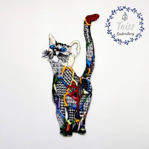 May include: A colorful embroidered cat patch with a black and white patterned design. The cat is standing with its tail raised in the air. The patch is perfect for adding a unique touch to clothing, bags, or other accessories.