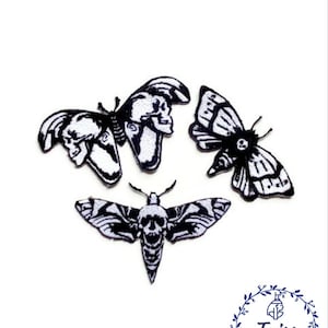 Puede incluir: Tres parches bordados en blanco y negro de polillas con detalles de calavera. Los parches son para ropa, bolsos u otros artículos de tela.